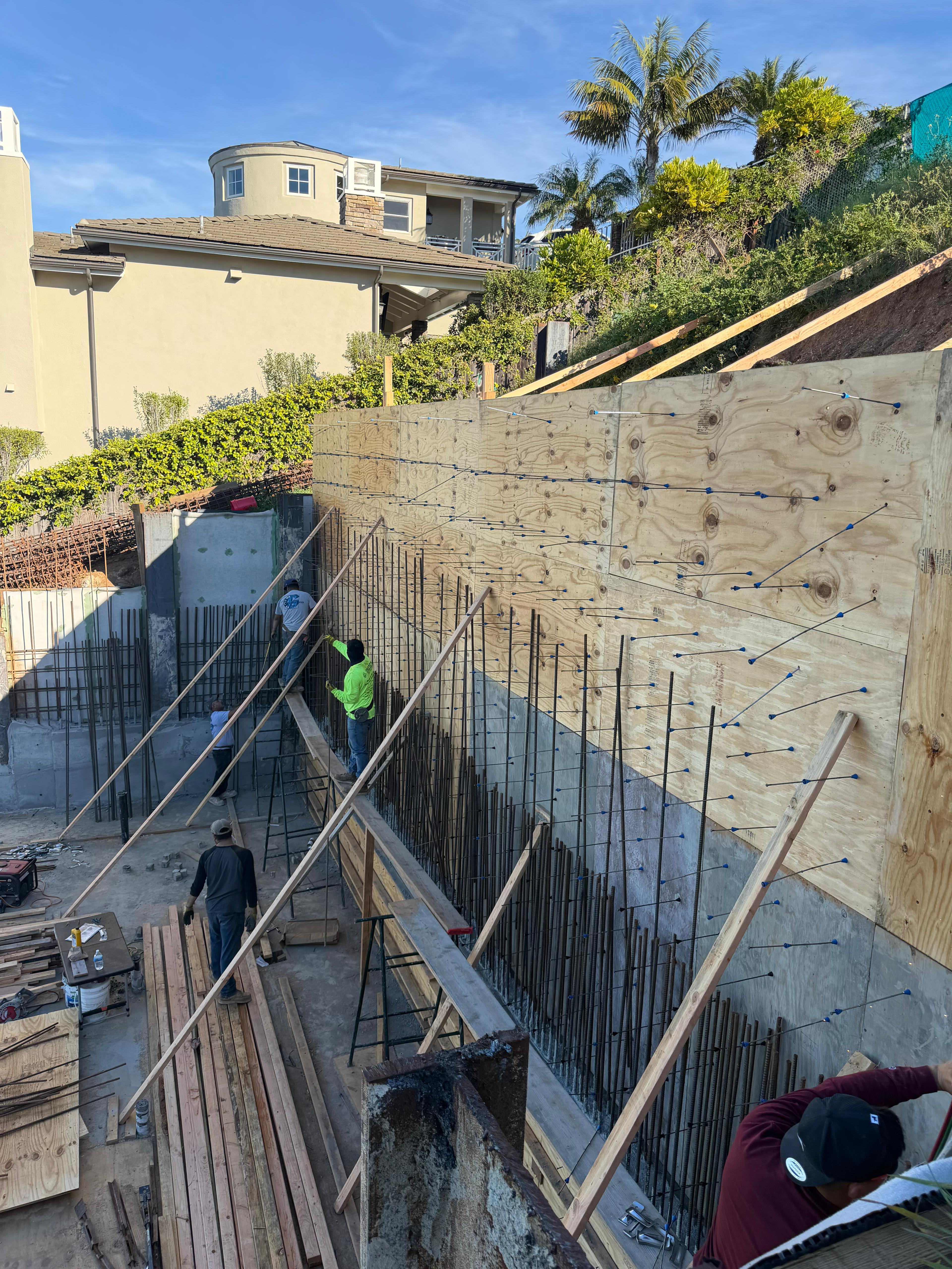Crew forming rebar for retaining wall on hillside site